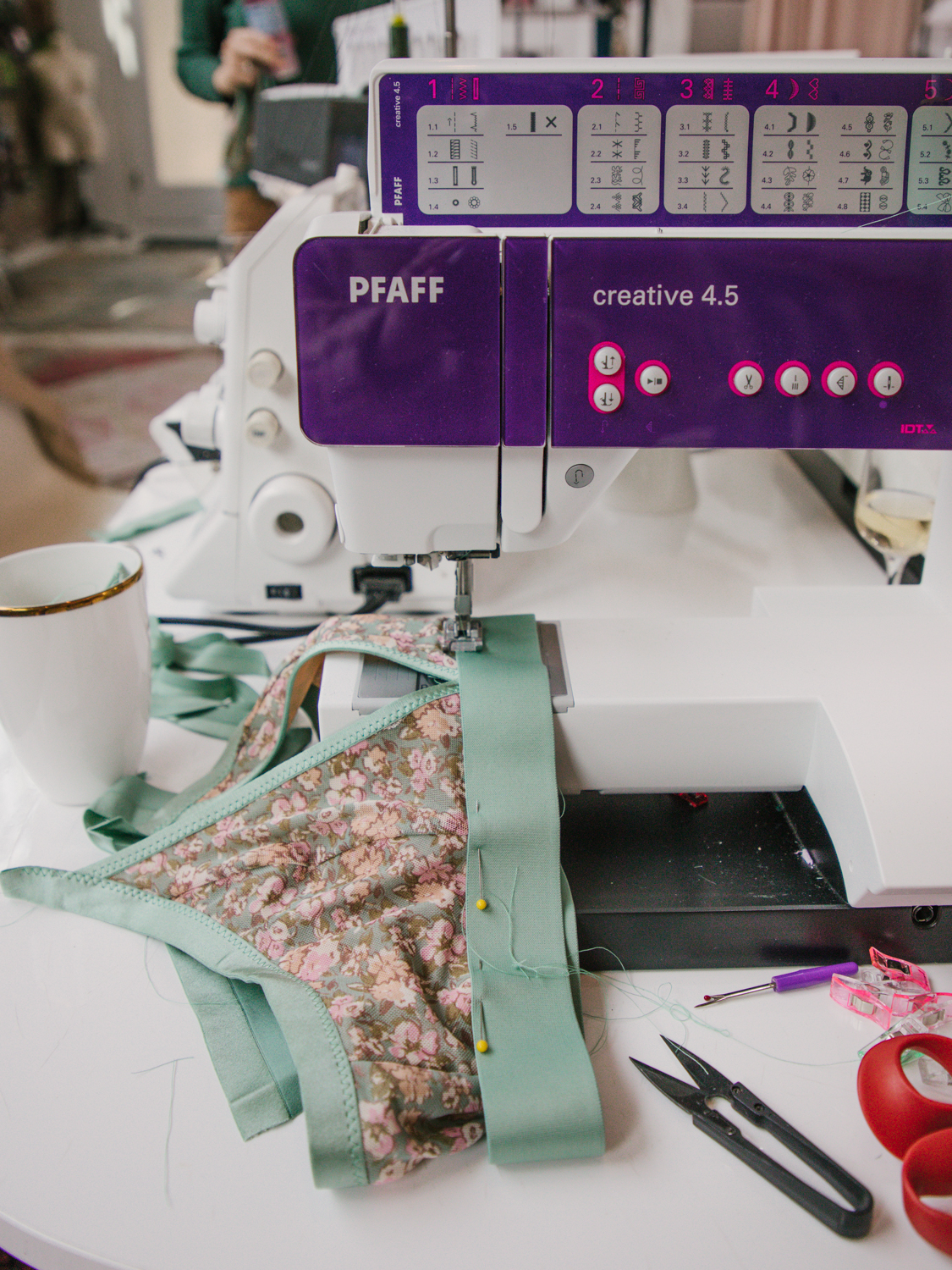 light green elastic bra band being sewn to printed fabric bralette on a Pfaff sewing machine